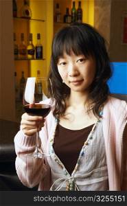 Portrait of a young woman holding a glass of red wine