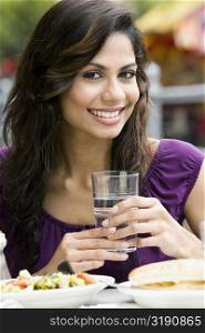 Portrait of a young woman holding a glass of water and smiling
