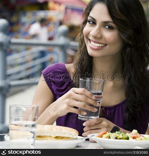 Portrait of a young woman holding a glass of water and smiling