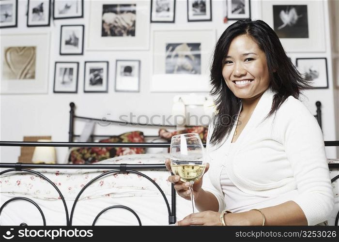 Portrait of a young woman holding a glass of wine smiling