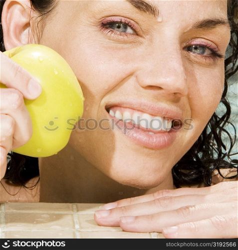 Portrait of a young woman holding a green apple in a swimming pool