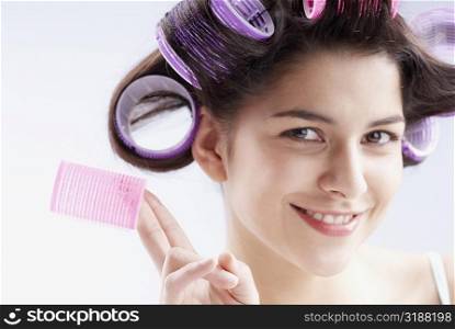 Portrait of a young woman holding a hair curler