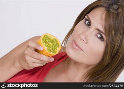 Portrait of a young woman holding a half kawani fruit