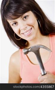 Portrait of a young woman holding a hammer and smiling