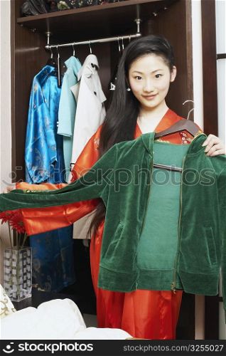 Portrait of a young woman holding a hooded shirt on a hanger