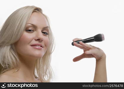 Portrait of a young woman holding a make-up brush