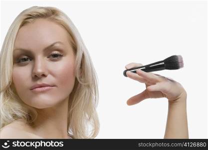 Portrait of a young woman holding a make-up brush