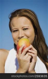 Portrait of a young woman holding a mango and smiling