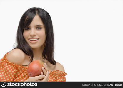 Portrait of a young woman holding a mango and smiling