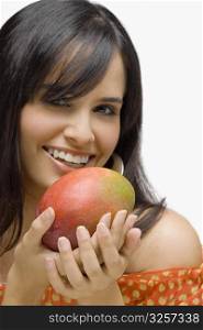 Portrait of a young woman holding a mango and smiling