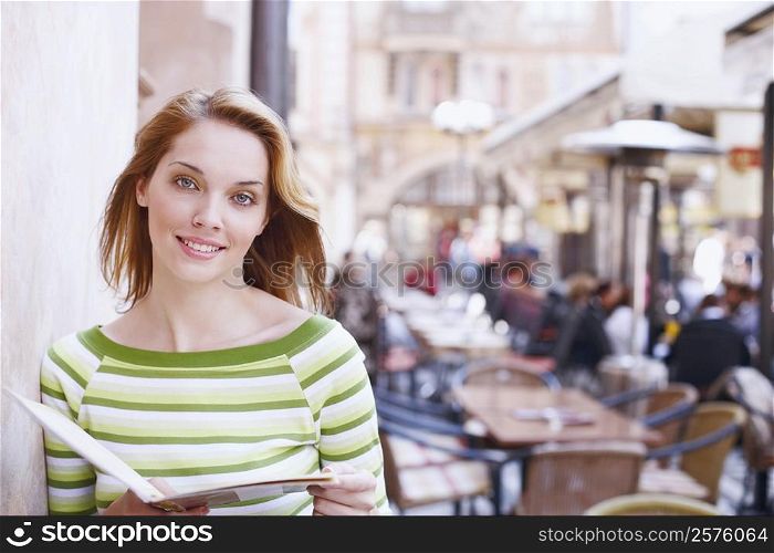 Portrait of a young woman holding a menu card