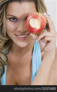 Portrait of a young woman holding a missing bite apple and smiling