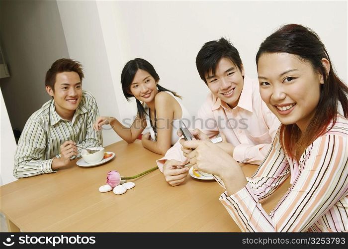 Portrait of a young woman holding a mobile phone and sitting with her friends