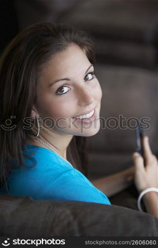 Portrait of a young woman holding a mobile phone and smiling