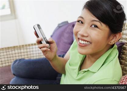 Portrait of a young woman holding a mobile phone and smiling
