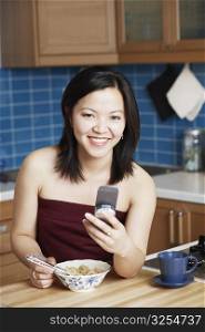 Portrait of a young woman holding a mobile phone smiling