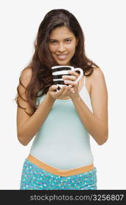 Portrait of a young woman holding a mug of coffee and smiling