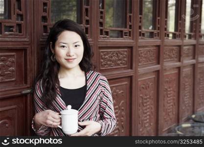 Portrait of a young woman holding a mug with a lid smiling