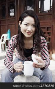 Portrait of a young woman holding a mug with a lid smiling