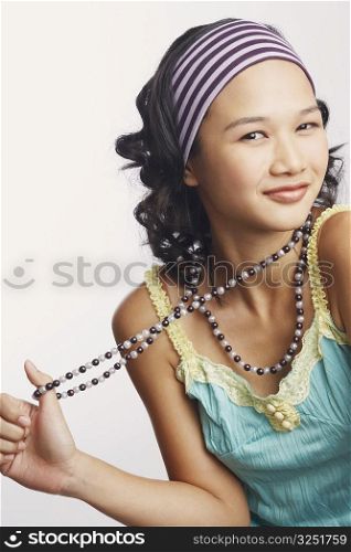 Portrait of a young woman holding a necklace and smiling