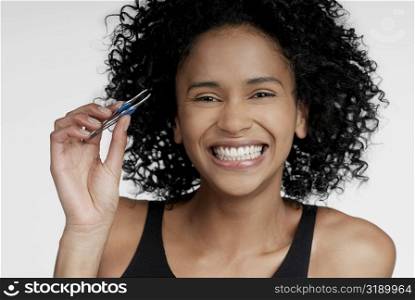 Portrait of a young woman holding a pair of eyebrow tweezers