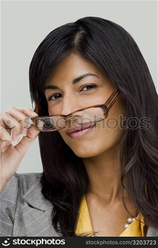 Portrait of a young woman holding a pair of eyeglasses