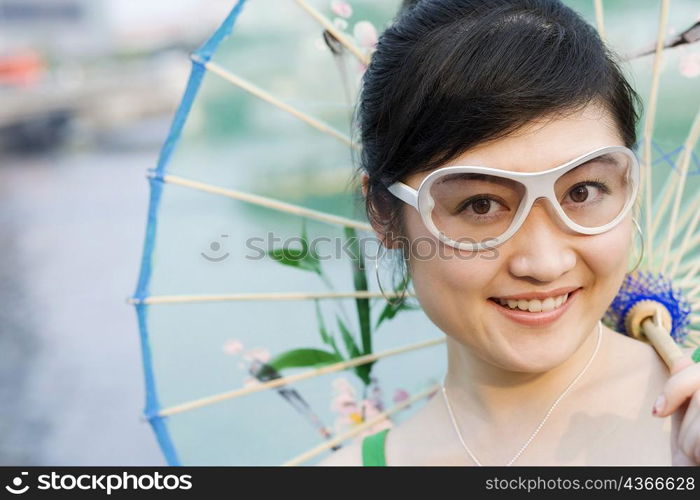 Portrait of a young woman holding a parasol and smiling