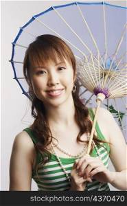 Portrait of a young woman holding a parasol and smiling
