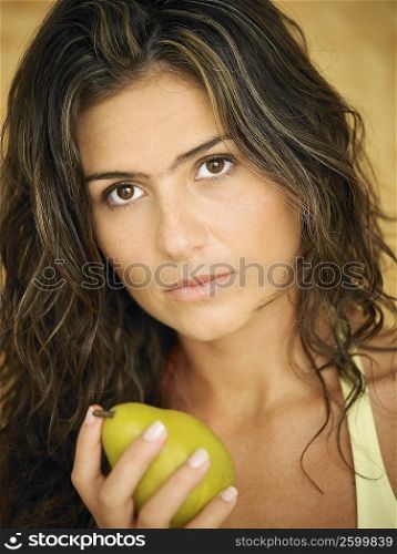 Portrait of a young woman holding a pear