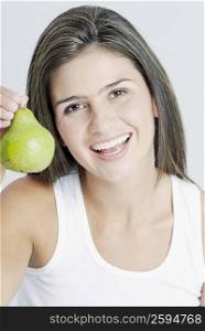 Portrait of a young woman holding a pear and smiling