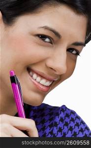 Portrait of a young woman holding a pen and smiling
