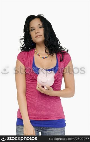 Portrait of a young woman holding a piggy bank