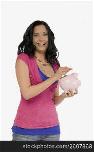 Portrait of a young woman holding a piggy bank and smiling