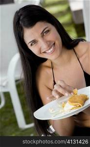 Portrait of a young woman holding a plate of food
