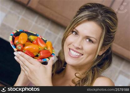 Portrait of a young woman holding a plate of red chili peppers