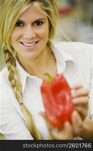 Portrait of a young woman holding a red bell pepper