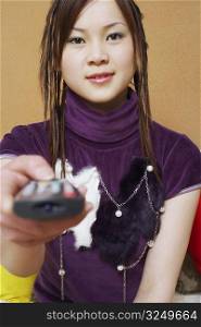 Portrait of a young woman holding a remote control