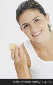 Portrait of a young woman holding a slice of lime and smiling