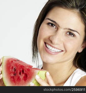 Portrait of a young woman holding a slice of watermelon and smiling