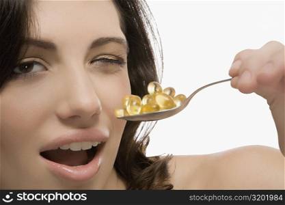 Portrait of a young woman holding a spoon full of pills