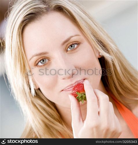 Portrait of a young woman holding a strawberry