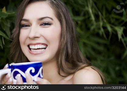 Portrait of a young woman holding a tea cup and smiling