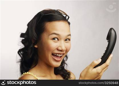 Portrait of a young woman holding a telephone and smiling