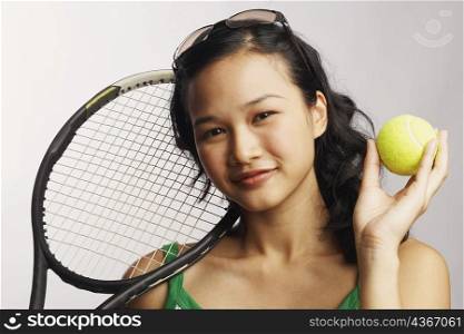 Portrait of a young woman holding a tennis ball and a tennis racket