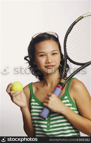 Portrait of a young woman holding a tennis racket and a tennis ball