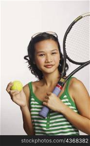 Portrait of a young woman holding a tennis racket and a tennis ball