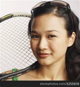 Portrait of a young woman holding a tennis racket and smiling
