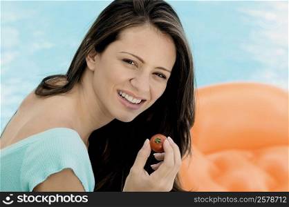 Portrait of a young woman holding a tomato