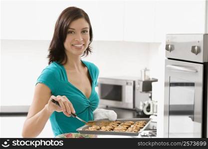 Portrait of a young woman holding a tray of cookies and smiling