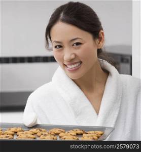 Portrait of a young woman holding a tray of cookies and smiling
